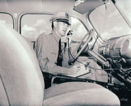 A DPS trooper talks on his car radio in this undated photo. (Based on the uniform and the fact he's in a car, this photo is most likely from the late 1940s or early 1950s.
